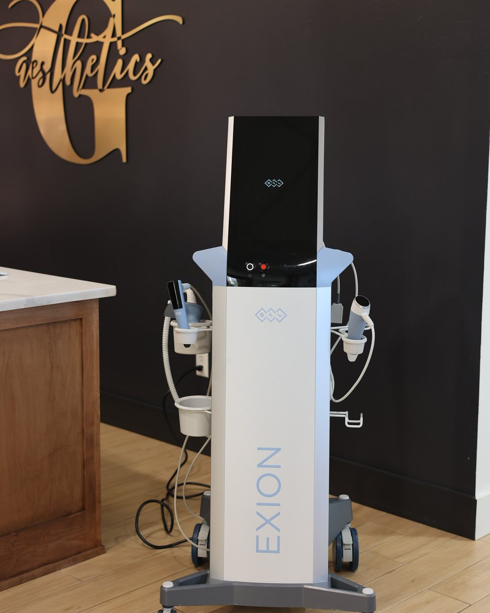 The BTL Exion console standing beneath the gold Gudgel Aesthetics wall mark