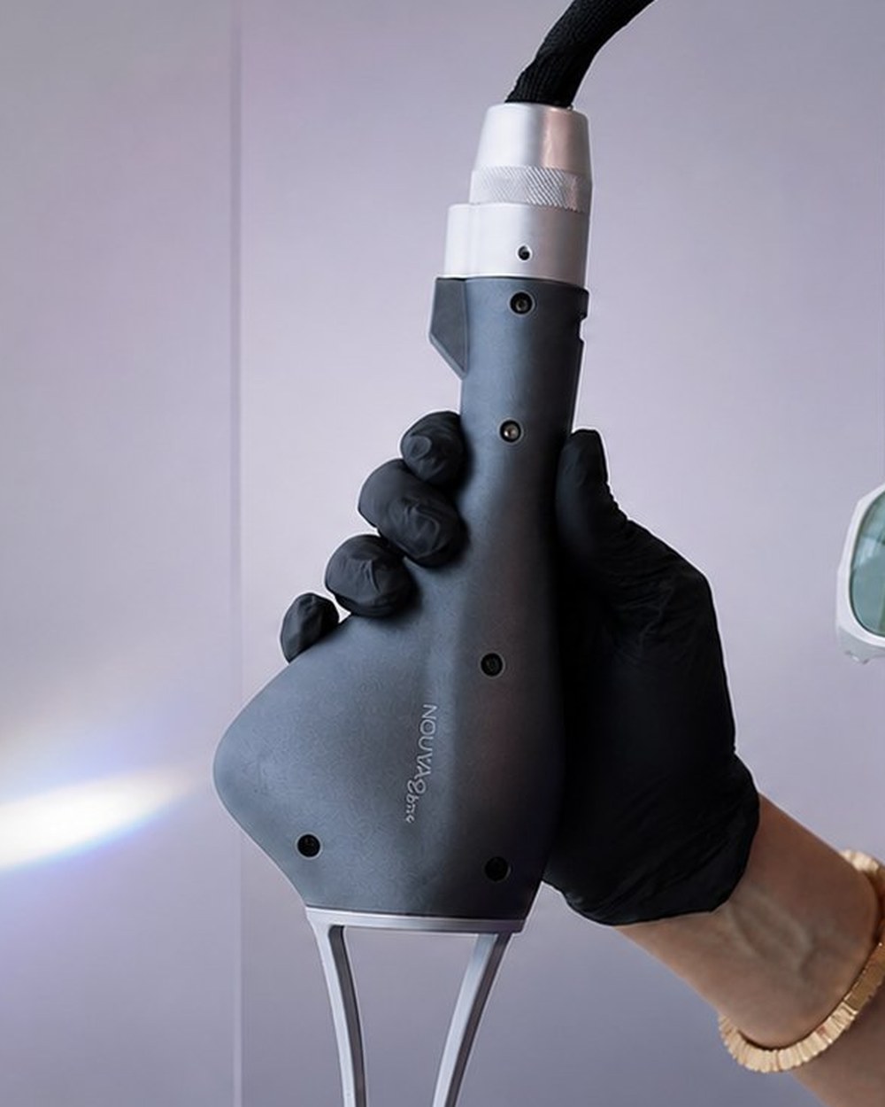 The NOUVAglow handpiece held in a gloved hand