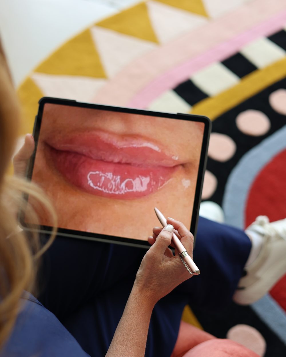A provider reviewing a lip treatment plan on a tablet at Gudgel Aesthetics